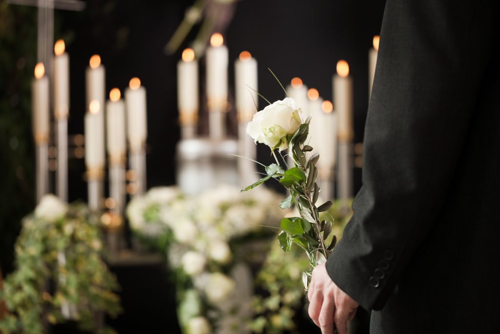 Religion, death and dolor - man at funeral with white rose mourning the dead