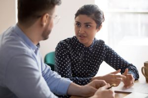 Young man and woman sitting at table talking together