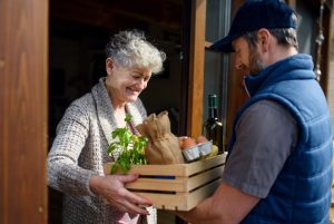Man delivering crate of groceries to older woman