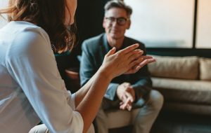 Adult man and woman sitting across from each other, woman talking while man listens