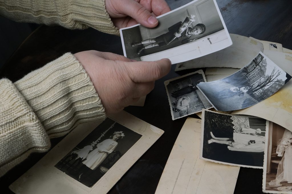 female hands fingering old photographs of 1950s, stack of photos on the table, concept of genealogy, memory of ancestors, family tree, nostalgia, childhood, remembering