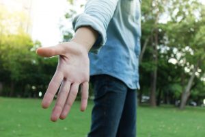 man in a blue shirt offering his hand to help someone up