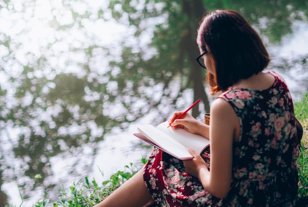 beautiful woman writing into her diary, in the park