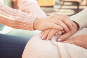 woman kindly holding another woman's hand in caring gesture