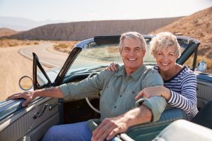 Mature couple sitting in their car out on a picturesque highway, fulfilling a bucket list item