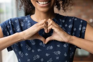 Young woman in navy blue shirt making a heart with her hands