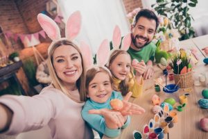 Family of 4 posing with Easter bunny ears and dyeing eggs