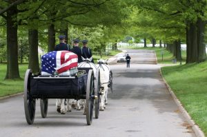 Shows military funeral procession at Arlington National Cemetery complete with horse-drawn caisson
