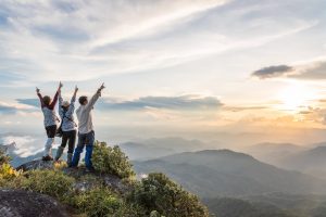 Three friends celebrating as they summit a mountain after a hike together