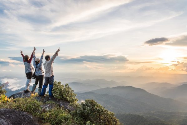 Three friends celebrating as they summit a mountain after a hike together