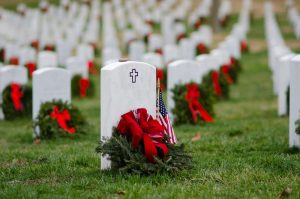 Shows beautiful wreaths with red bows leaning against veteran graves