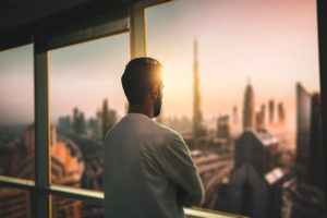 man standing at window looking at city