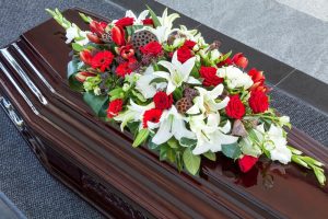 Decorative red and white flowers laying on top of closed casket