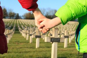Parent holding a child's hand in a cemetery