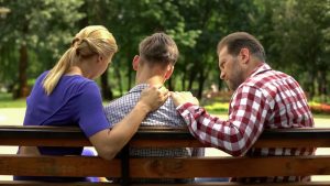 parents comforting teenage son