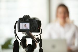 Foreground with camera on tripod with blurred background of woman leaving a review