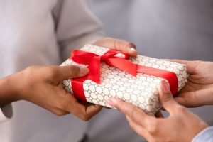 One person giving a wrapped gift to another person