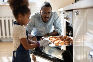 Dad and daughter making homemade muffins in kitchen