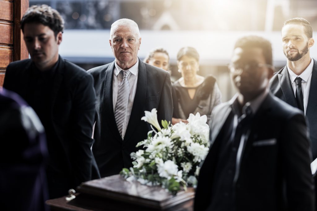 Sad, funeral and people with coffin at church for service, mourning and grief over death.