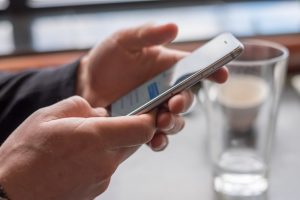 Focus on a man's hands as he holds his smartphone and reads his text messages