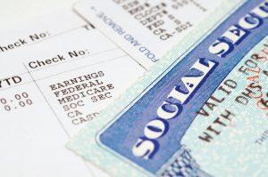 Social Security card in the foreground with paycheck in the background