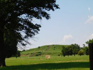Cahokia Mound in the distance, a large, grass-covered hill below blue sky