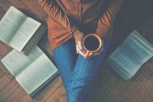 Woman sitting on floor with three open books lying beside her