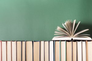 A row of books with one open book sitting on top