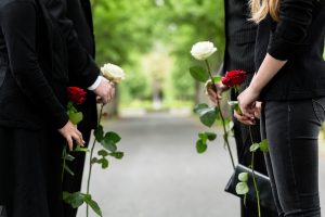 Family of four wearing black, each holding a white or red flower of remembrance