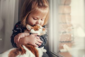 young girl hugging a cat