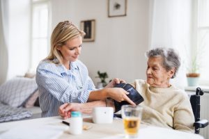 Younger woman checking older woman's blood pressure at home
