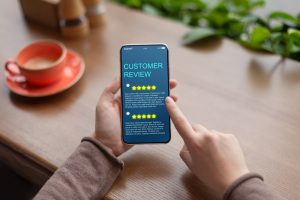 Woman sitting at home looking at online reviews on her phone, focus on phone and woman's hands only