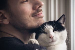 man holding a black and white cat