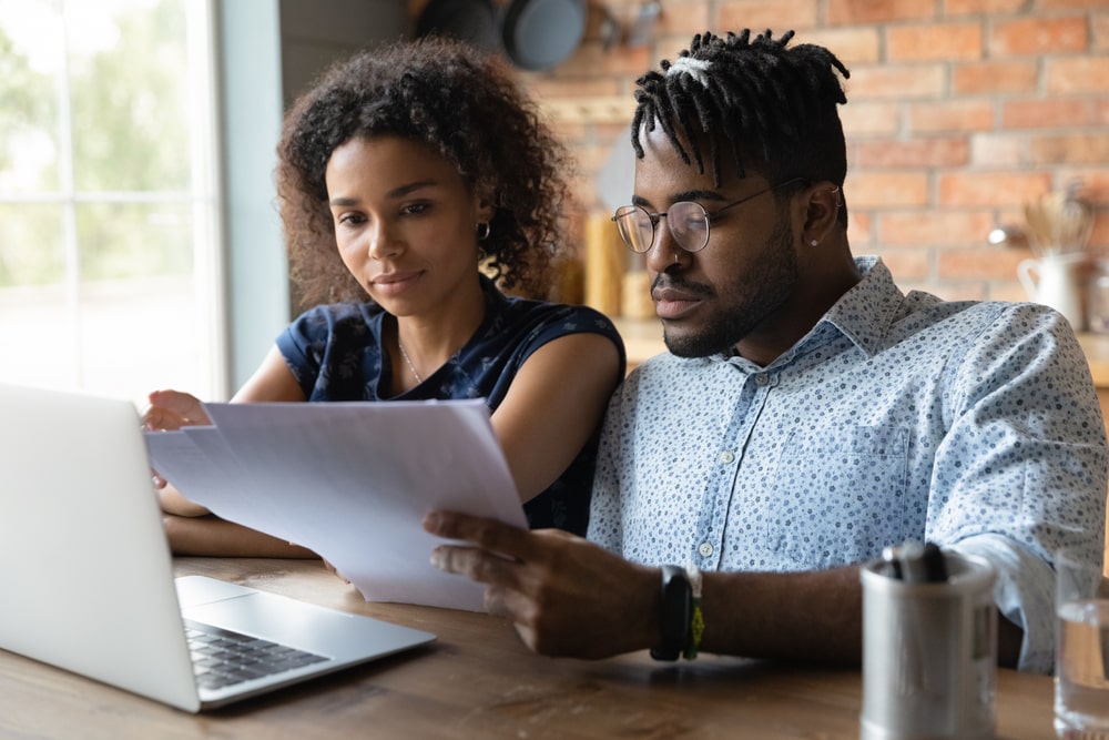 Couple sitting at table at home, reviewing an itemized statement