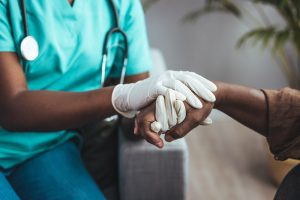 Nurse holding the hand of a hospice patient