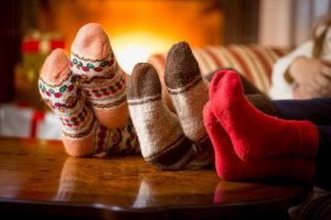 Group of three sitting quietly at home, sitting next to a warm fire and wearing cozy socks
