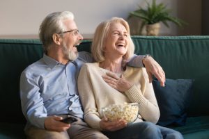 elderly couple laughing together while watching a movie