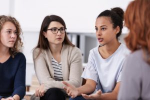 Group of four women in a support group listening to one talk and share