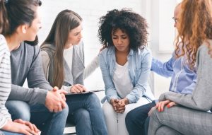 Grief support group offering support to a young woman as she looks sad