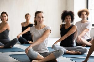 Groups class sitting on exercise mats and stretching after a workout