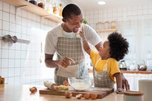 Father and young daughter baking together, smiling and having a good time