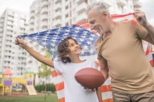 Grandfather and grandson smiling together and going to play American football