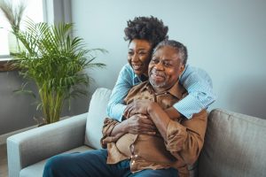 adult daughter hugging and smiling with elderly father