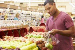 Young man at grocery store selecting apples to buy