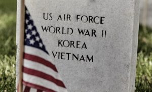 Close-up of military headstone with American flag nearby