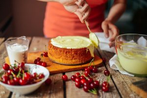 Woman wearing an orange shirt as she frosts a cake