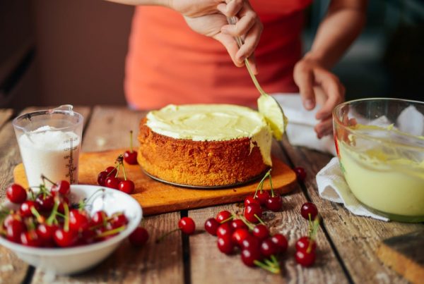 Woman wearing an orange shirt as she frosts a cake