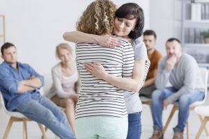 Two women sharing a hug at a grief support group