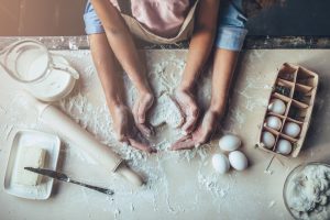 A man and a woman baking together, with ingredients laid out on counter