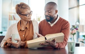 Man and wife sitting at table together, looking at book and making choices for funeral
